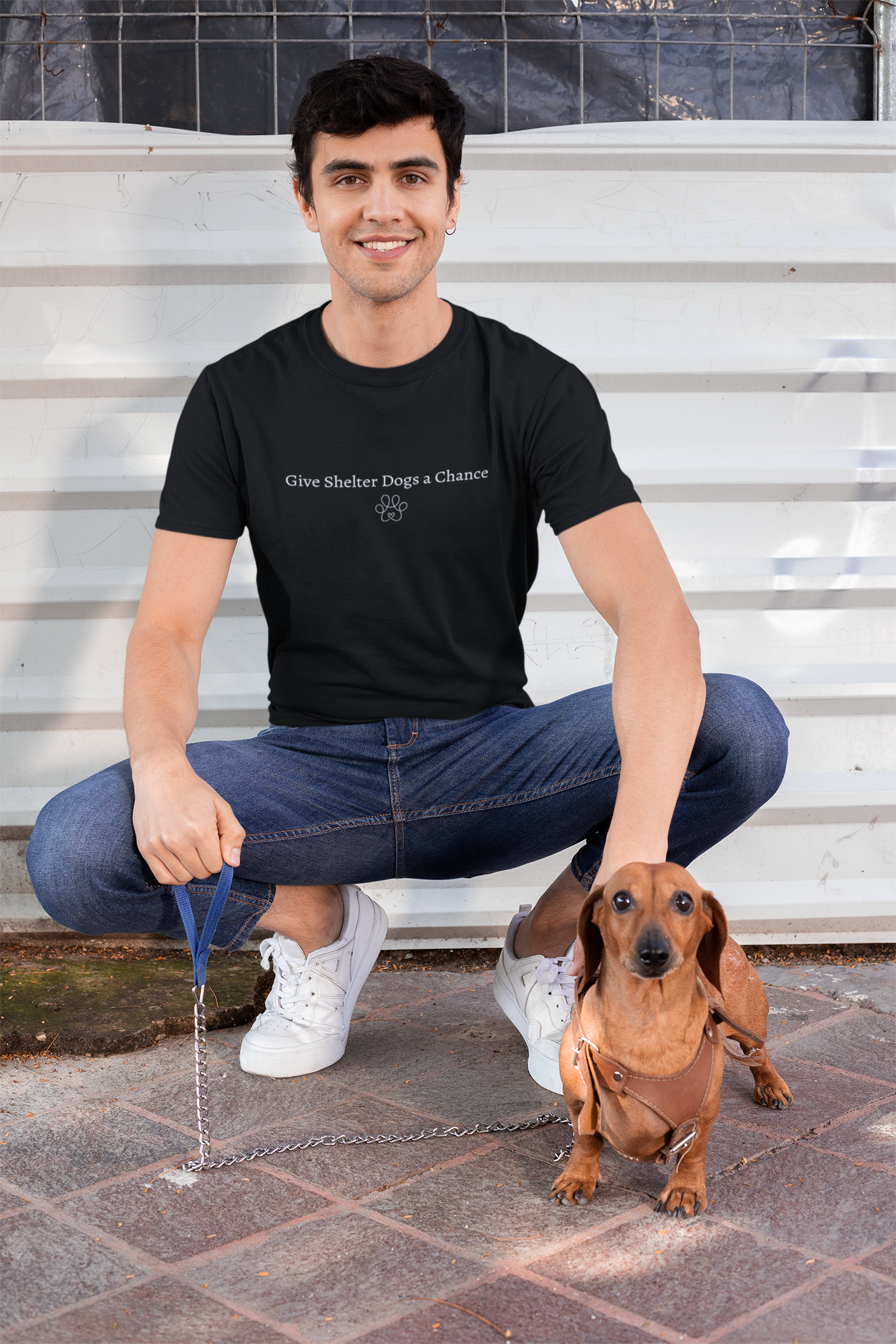 Man sitting on steps with a dachshund wearing a black t-shirt with Give Shelter Dogs a Chance text.