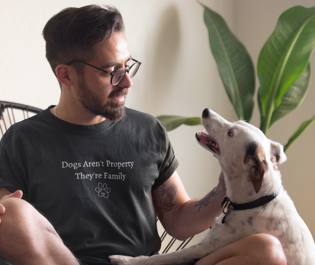 Man sitting on a chair with a dog, wearing a t-shirt with a message about dogs.